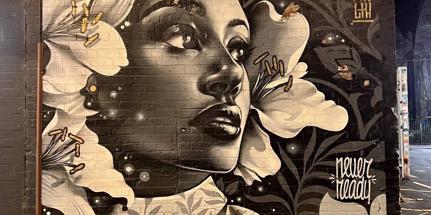 portrait of a woman surrounded by flowers painted onto a wall in street art style